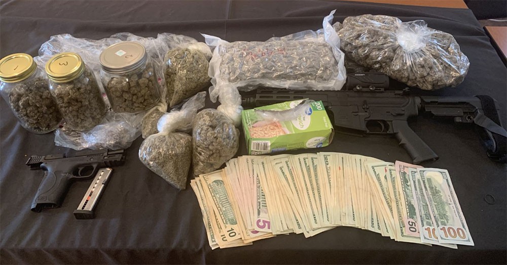 Items seized during execution of search warrant including weapons, drugs, and cash. 